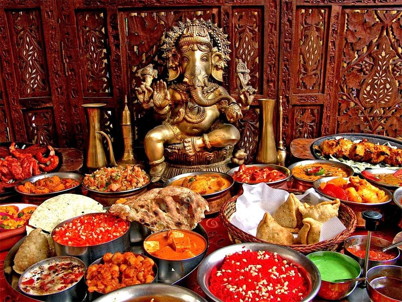 Table remplie de plats indien et une statue de Shiva. Restaurants Indien à Lyon